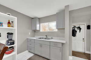 Kitchen featuring gray cabinets, light countertops, light marble finish flooring, and open shelves