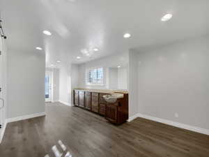 Bar area with recessed lighting, dark wood finished floors, and brown cabinets