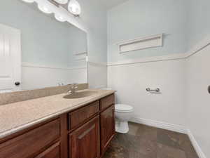 Bathroom with wainscoting, vanity, and stone tile flooring