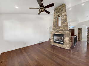 Unfurnished living room featuring arched walkways, a fireplace, dark wood-style flooring, a ceiling fan, and recessed lighting