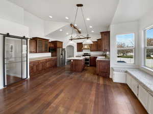 Kitchen with a kitchen island, a barn door, hanging light fixtures, glass insert cabinets, and stainless steel appliances