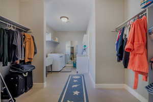Walk in closet with independent washer and dryer and light tile patterned flooring