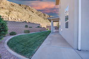 Yard at dusk featuring a fenced backyard, a mountain view, and a patio
