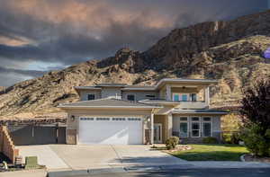 Prairie-style home featuring a balcony, driveway, stucco siding, a mountain view, and ceiling fan