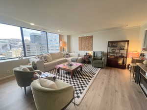 Living room with light wood-style flooring, a city view, and ornamental molding