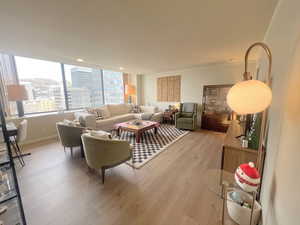 Living area featuring light wood-type flooring, a city view, and ornamental molding