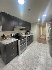 Kitchen with stainless steel appliances, dark cabinetry, and under cabinet range hood