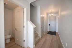 Corridor with light wood-style floors and a chandelier