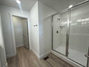 Full bath featuring recessed lighting, light wood-style floors, and a shower stall