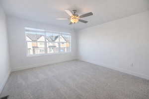 Carpeted spare room featuring baseboards and ceiling fan