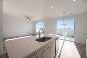 Kitchen featuring decorative light fixtures, light wood-style floors, open floor plan, light stone counters, and ceiling fan