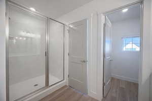 Full bathroom with light wood-style flooring, a stall shower, and recessed lighting