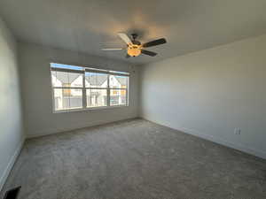 Carpeted spare room with baseboards and ceiling fan