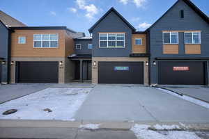 Modern home featuring brick siding, driveway, an attached garage, and a standing seam roof