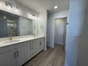 Full bathroom with a stall shower, double vanity, and light wood-style flooring