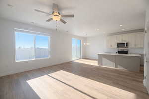 Kitchen with a center island with sink, open floor plan, recessed lighting, light wood-style flooring, and appliances with stainless steel finishes