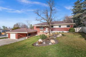 View of front facade with brick siding, driveway, a garage and carport