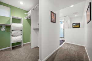 Spacious closet with light carpet and attached 3/4 bathroom