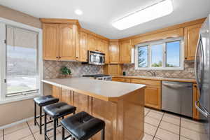 Kitchen with south & western views, countertop bar seating, tile backsplash & flooring