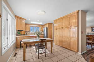 Kitchen with countertop bar seating, dining table area and plenty of wood cabinetry storage