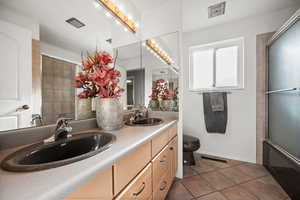 Full bathroom with double vanity and dark tile floors
