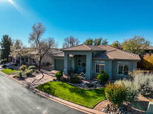 View of front of home with a front lawn, stucco siding, a garage, a tile roof, and driveway