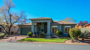 Prairie-style home with stucco siding, a porch, a front yard, a garage, and driveway