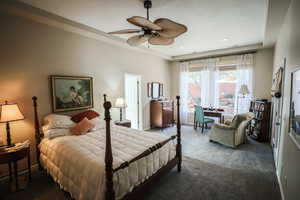 Bedroom with dark colored carpet, a ceiling fan, and a desk