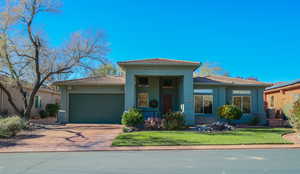 Prairie-style home with a porch, concrete driveway, a garage, and stucco siding