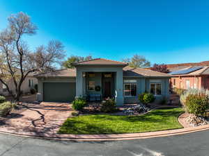 Prairie-style house with stucco siding, a porch, concrete driveway, a tiled roof, and a front lawn