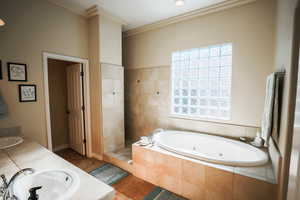 Bathroom featuring a whirlpool tub, double vanity, tile patterned floors, and ornamental molding