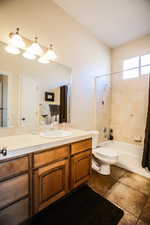 Bathroom featuring shower / tub combo with curtain, vanity, and dark tile patterned flooring