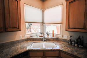 Kitchen with dark stone counters, a textured wall, and dishwasher