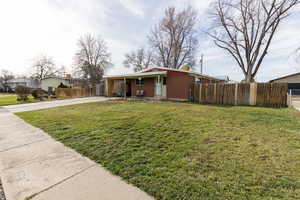 View of front of house with concrete driveway, brick siding, covered porch, and a chimney