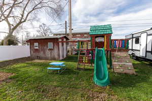 View of playground featuring a shed and a fenced backyard
