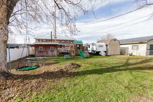Rear view of house with a storage shed, a fenced backyard, a playground, and a trampoline