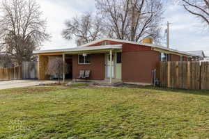 View of front of property featuring brick siding, covered porch, driveway, and a carport