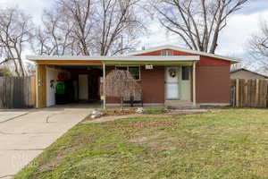 Ranch-style house featuring an attached carport, brick siding, driveway, and a porch