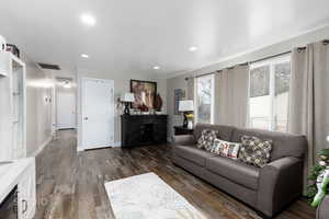 Living room with dark wood-style floors, recessed lighting, and wine cooler