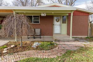 Entrance to property featuring covered porch and brick siding
