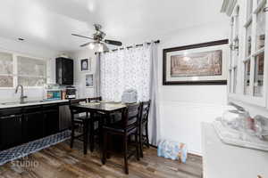 Dining space with wainscoting, dark wood-type flooring, and a ceiling fan