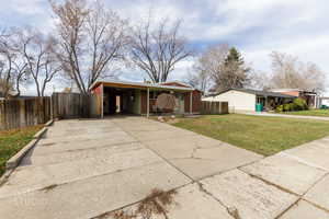 View of front facade featuring concrete driveway and a carport