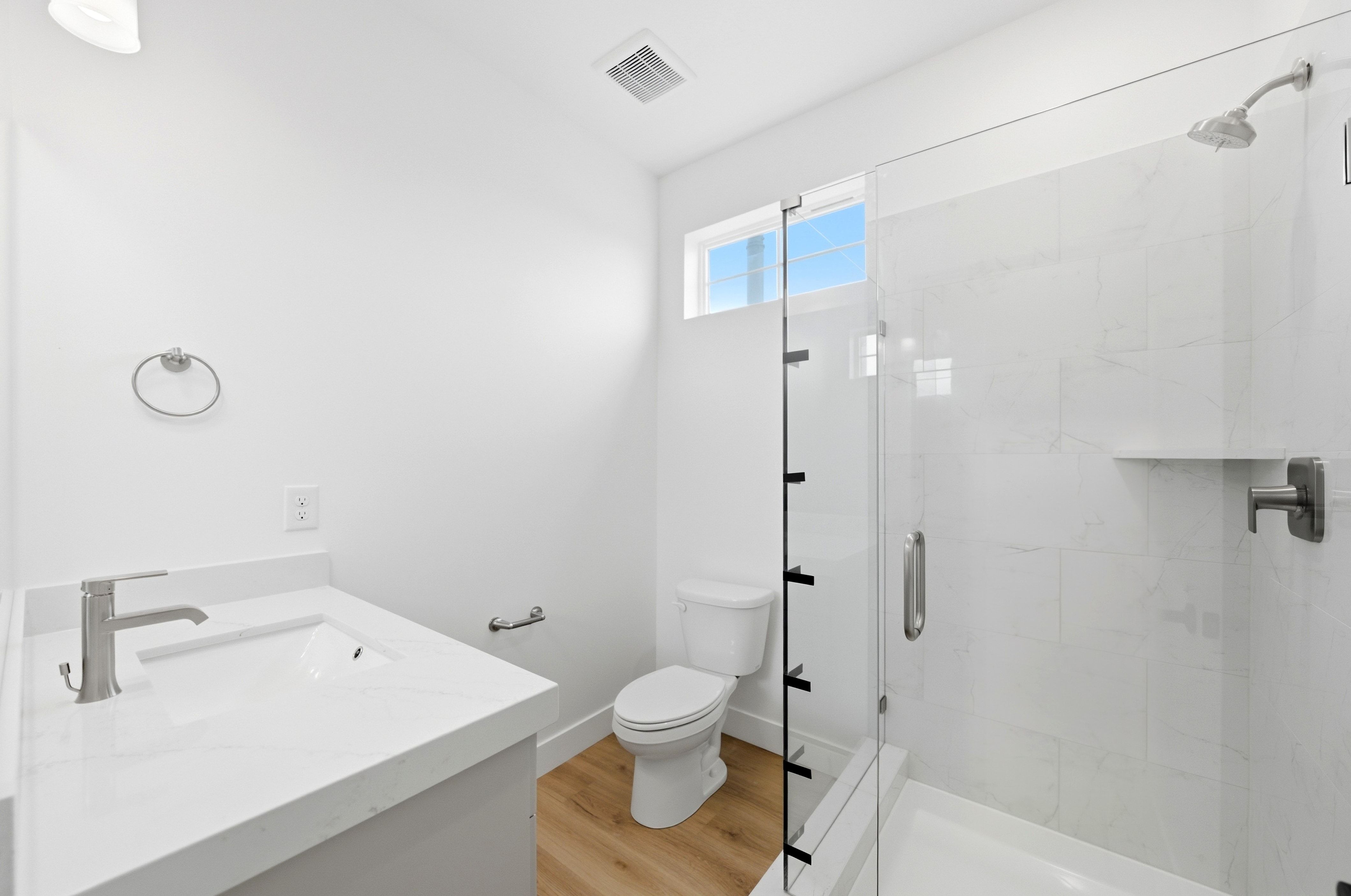 Contemporary bathroom featuring a frameless glass shower enclosure, a white tiled shower with an integrated shelf, and brushed nickel fixtures