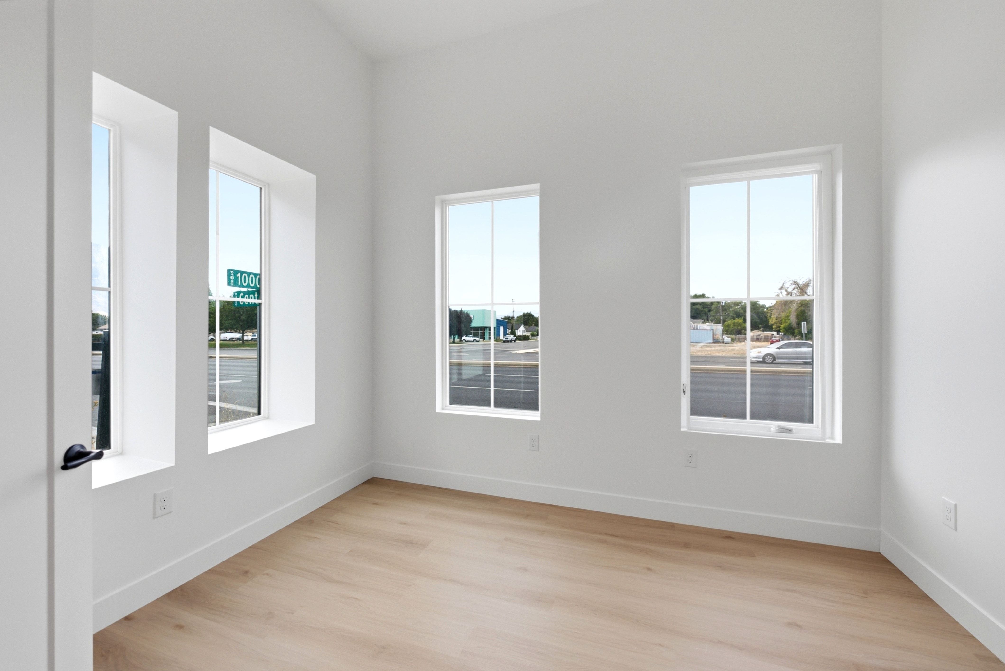 Bright interior space featuring multiple windows, white walls, light wood-finish flooring, and white baseboards