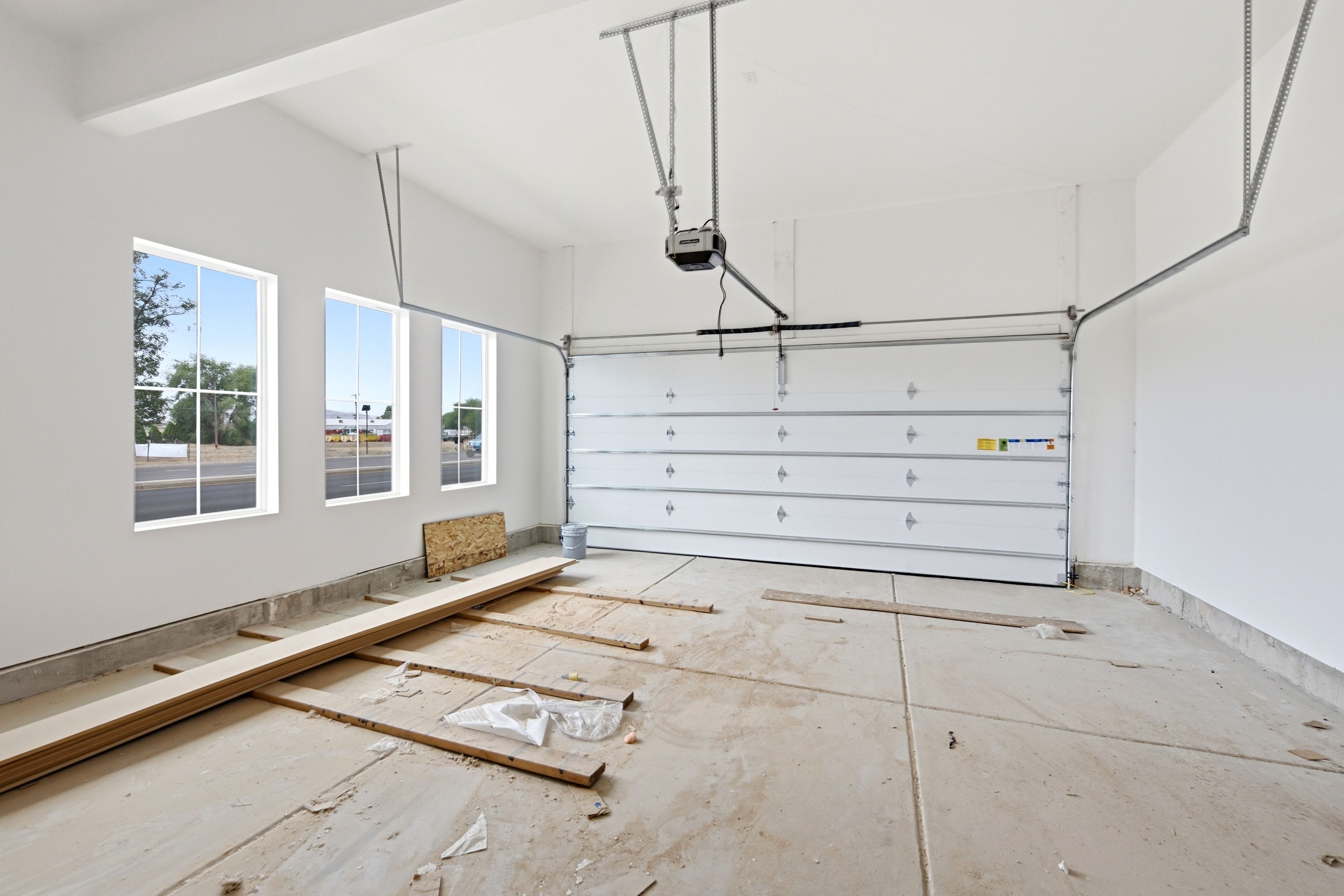Spacious garage featuring a concrete floor, three grid-pattern windows, and an automatic garage door opener system