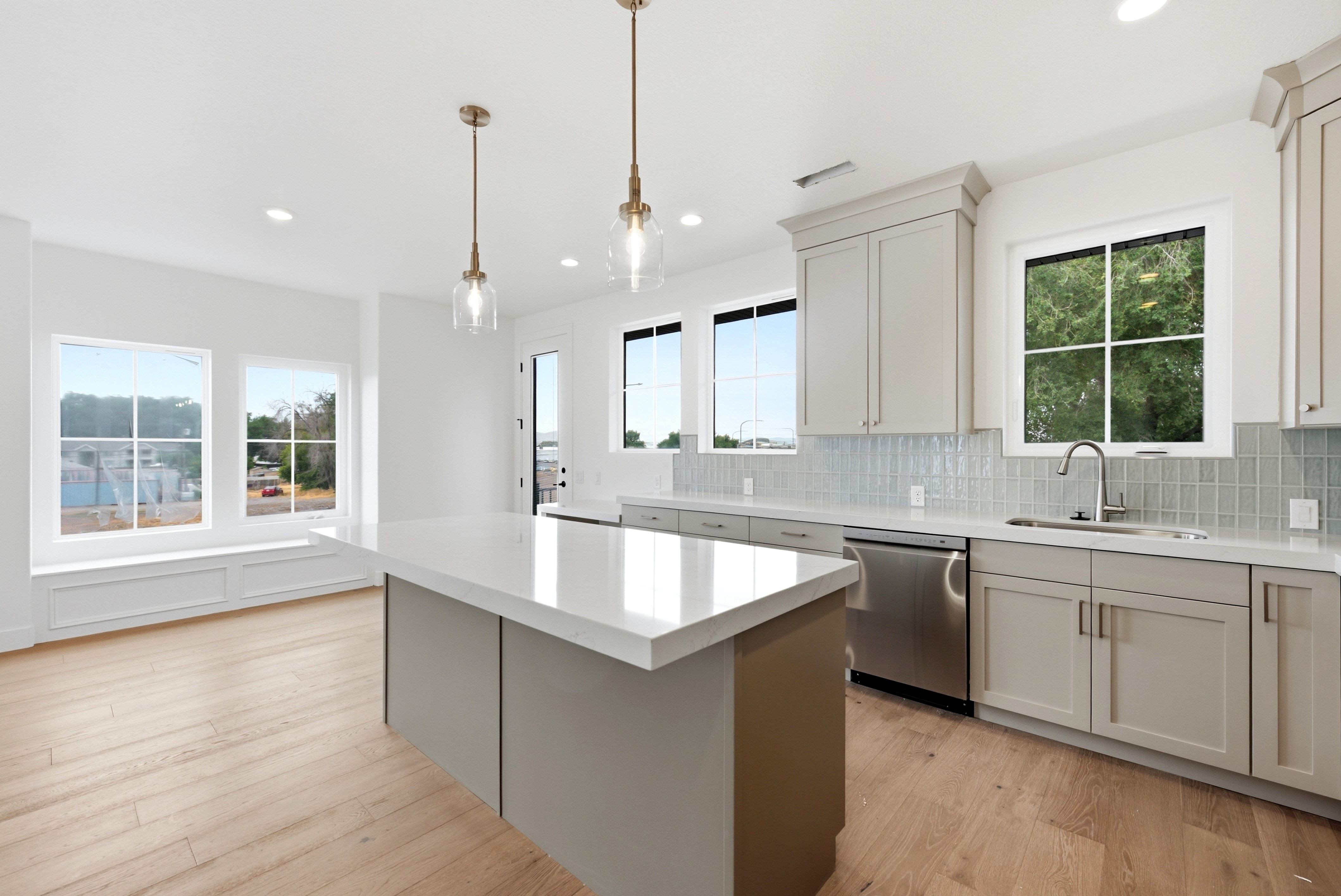 Modern kitchen featuring light wood-finish flooring, a large island with a light-colored countertop, and recessed lighting