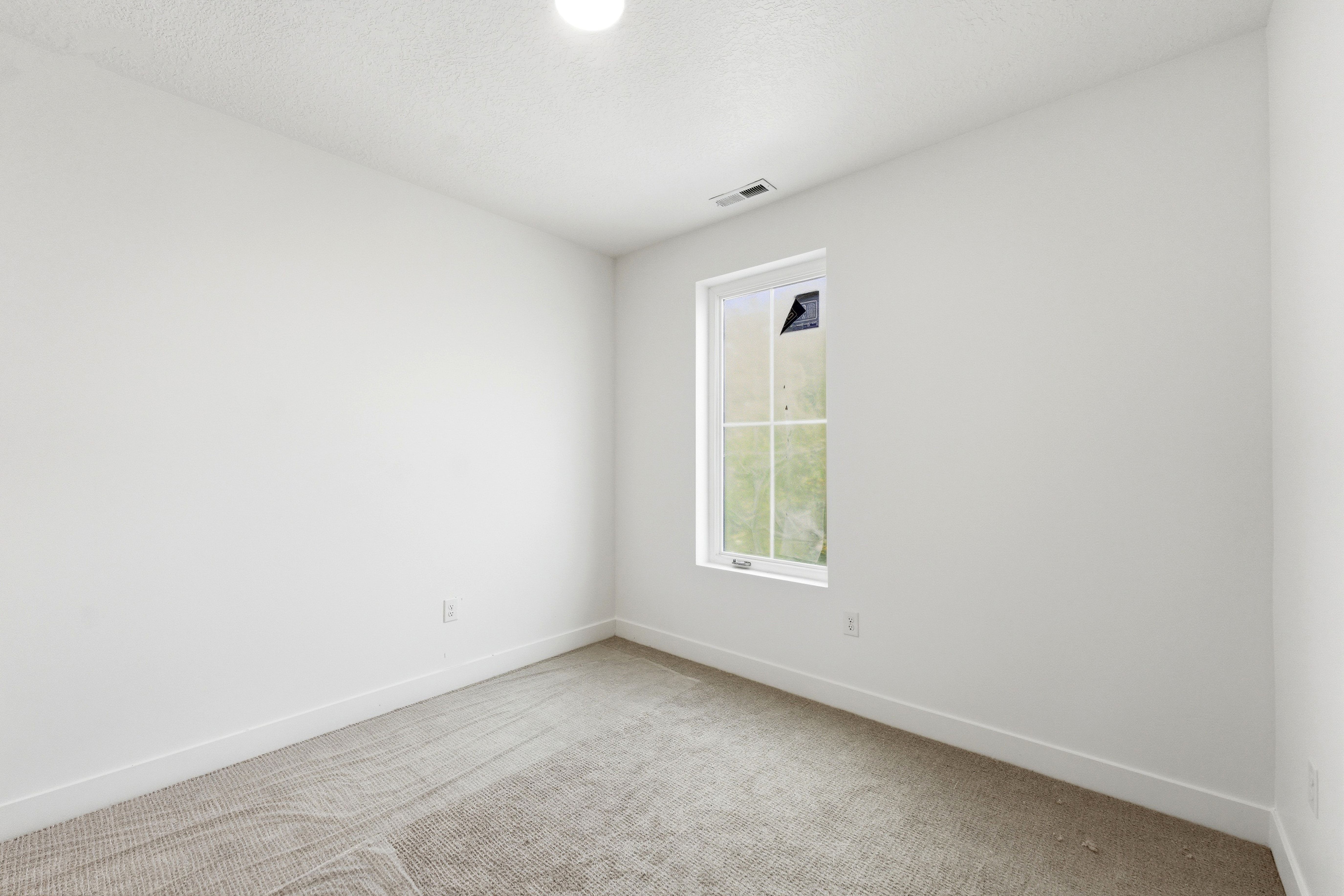 Empty room with light carpet and a textured ceiling