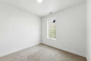 Empty room with light carpet and a textured ceiling