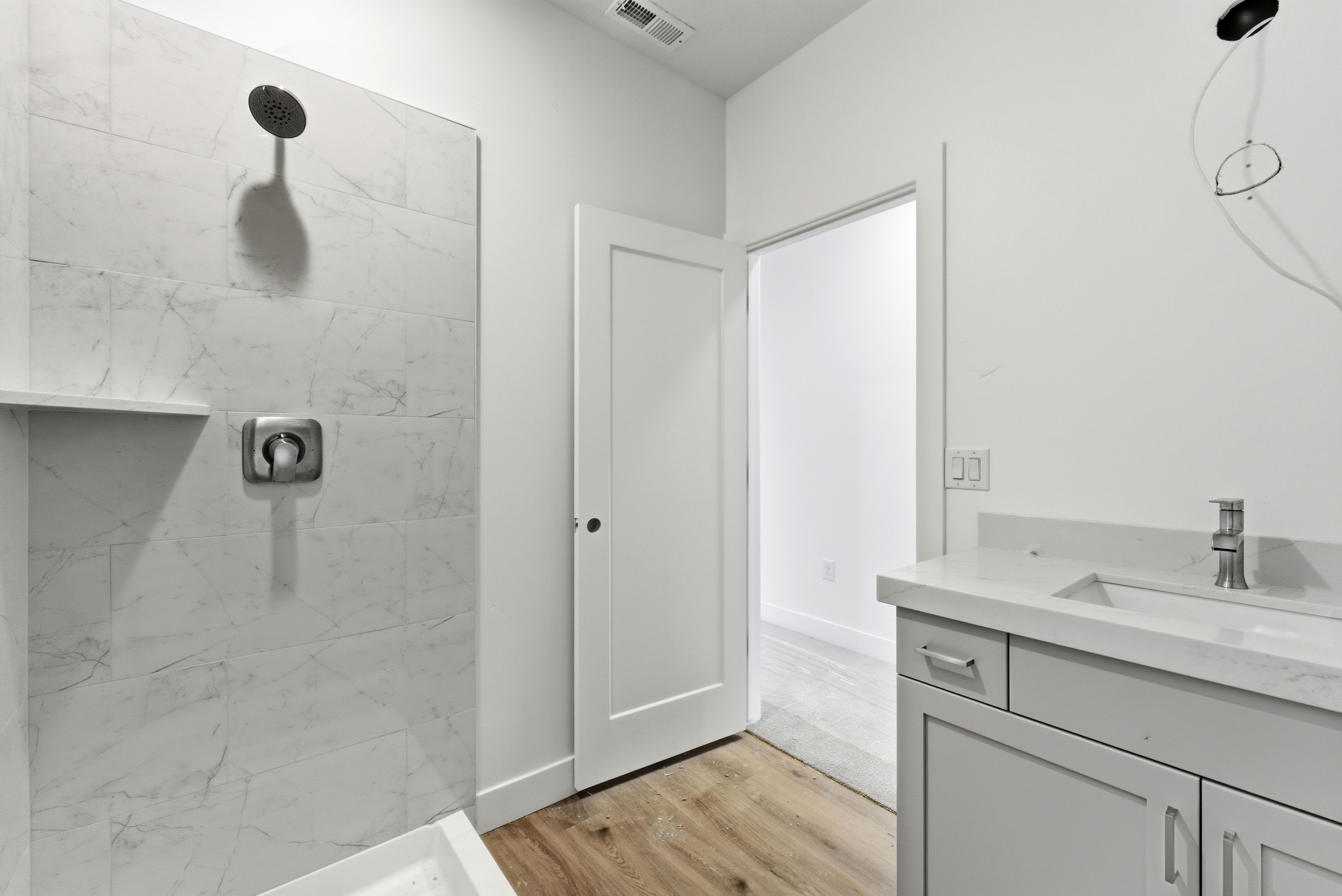 Full bathroom with vanity, a marble finish shower, and light wood-style floors