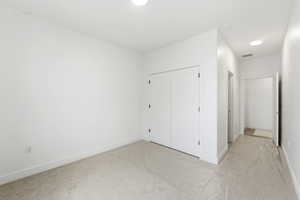 Unfurnished bedroom with light carpet, a closet, and recessed lighting